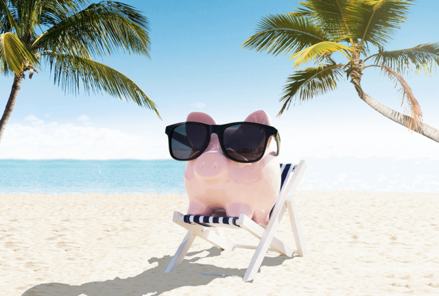 Piggy bank in a beach chair wearing sunglasses on a beach